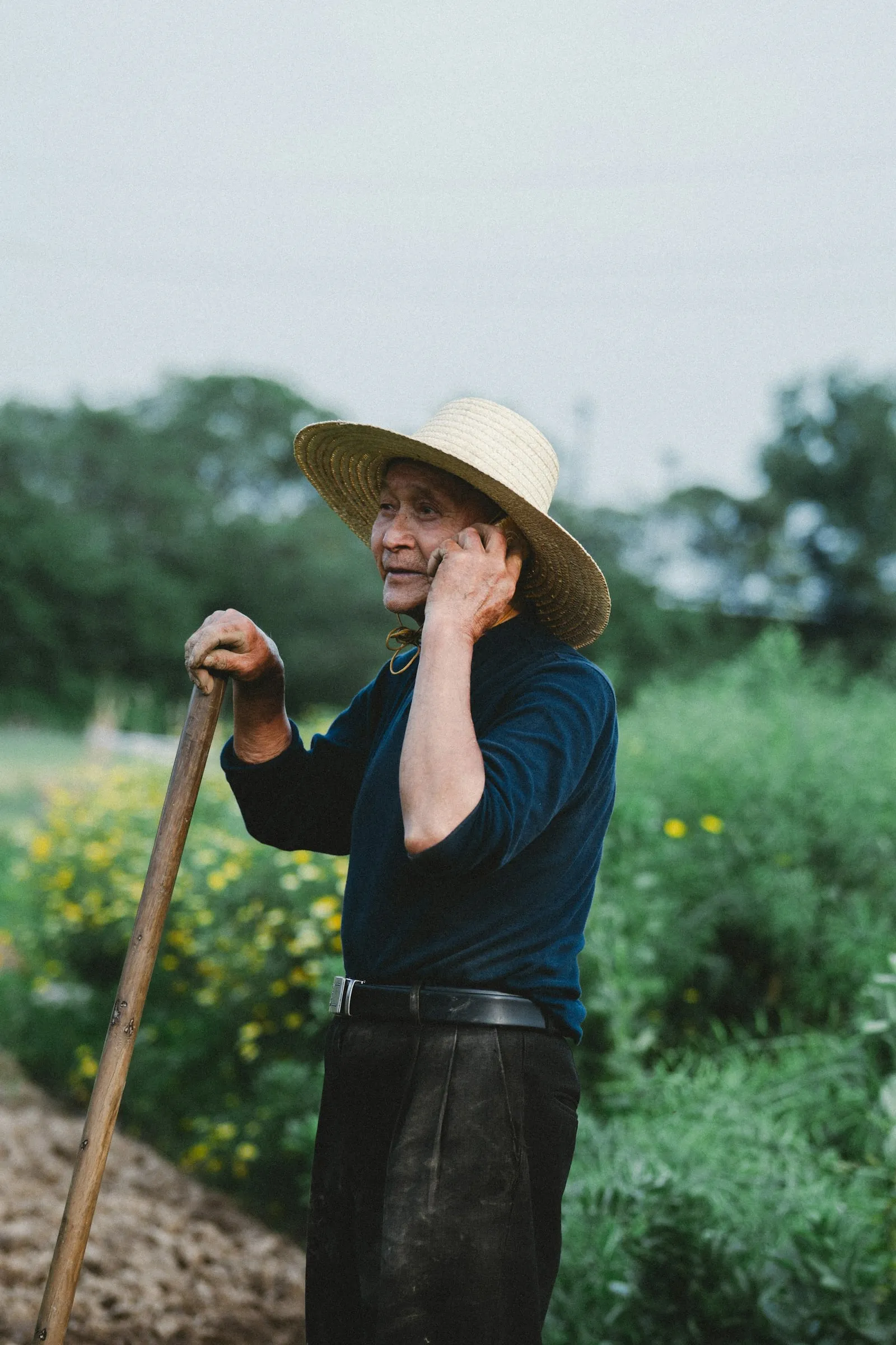 Illustrative photo: a farmer in a straw hat talking on his phone in a field