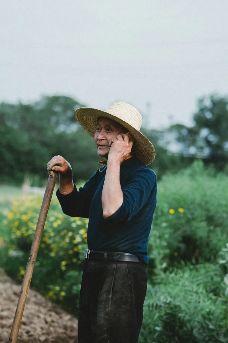Illustrative photo: a farmer in a straw hat talking on his phone in a field