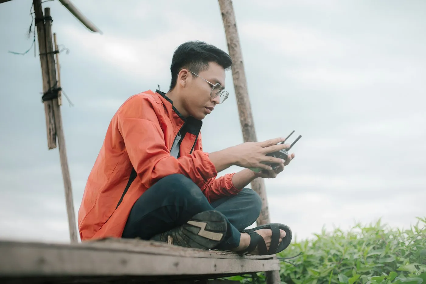 A man sitting outdoors, reading his phone